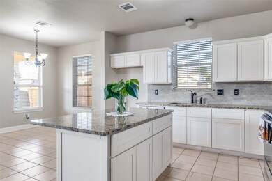 Kitchen with white cabinetry, a kitchen island, dark stone countertops, light tile patterned flooring, and backsplash