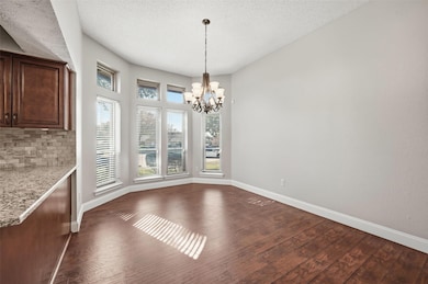 Unfurnished dining area with a textured ceiling, dark wood-style flooring, and a chandelier