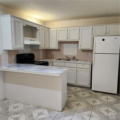 Kitchen with refrigerator, light countertops, decorative backsplash, a peninsula, and a textured ceiling
