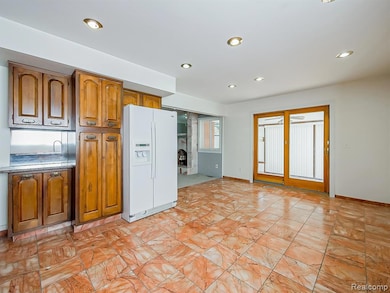 Kitchen with brown cabinetry, white refrigerator with ice dispenser, recessed lighting, and light countertops