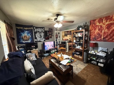 Living area featuring ceiling fan and a textured ceiling