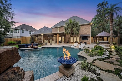 Pool at dusk with a gazebo, an outdoor living space with a fire pit, a fenced backyard, and a patio