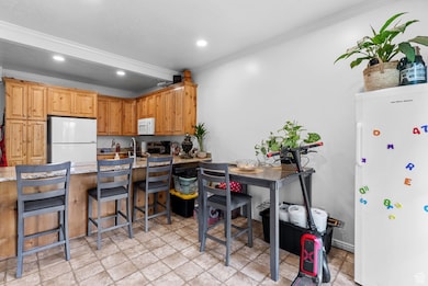 Kitchen featuring a peninsula, a kitchen bar, white appliances, crown molding, and recessed lighting