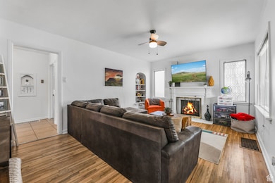 Living area featuring a fireplace with flush hearth, hardwood / wood-style floors, and a ceiling fan