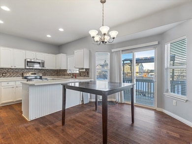 Kitchen featuring tasteful backsplash, white cabinetry, light countertops, dark wood finished floors, and recessed lighting