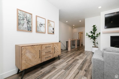 Living room with baseboards, a fireplace, wood finished floors, and recessed lighting