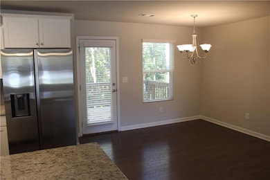 Kitchen featuring stainless steel fridge, dark wood-style flooring, hanging light fixtures, a chandelier, and white cabinets