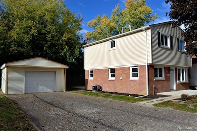 View of property exterior featuring brick siding, a garage, an outbuilding, and gravel driveway