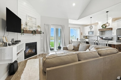 Living room featuring lofted ceiling, light wood finished floors, a fireplace, and recessed lighting