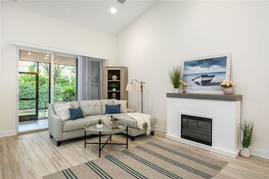 Living room featuring a glass covered fireplace, light wood finished floors, high vaulted ceiling, and recessed lighting
