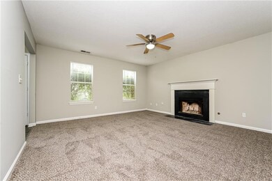Unfurnished living room featuring ceiling fan, carpet floors, and a fireplace with flush hearth