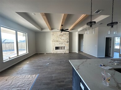 Unfurnished living room featuring beam ceiling, dark wood-style flooring, a stone fireplace, and ceiling fan