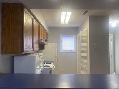 Kitchen with under cabinet range hood, white appliances, and brown cabinets