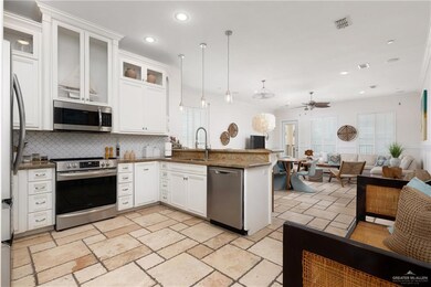 Kitchen with appliances with stainless steel finishes, a sink, a peninsula, open floor plan, and decorative backsplash