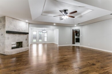 Unfurnished living room with dark hardwood / wood-style floors, ceiling fan, a raised ceiling, and a fireplace