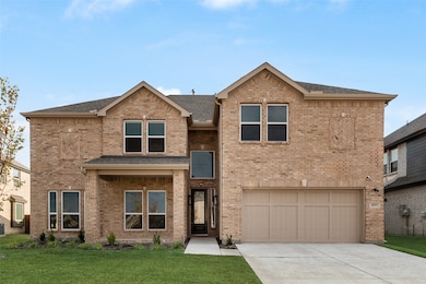 View of front facade with brick siding, a shingled roof, driveway, and a front yard