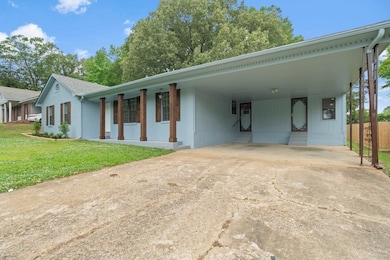 View of front facade with brick siding, an attached carport, and driveway