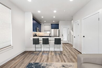 Kitchen with blue cabinetry, appliances with stai