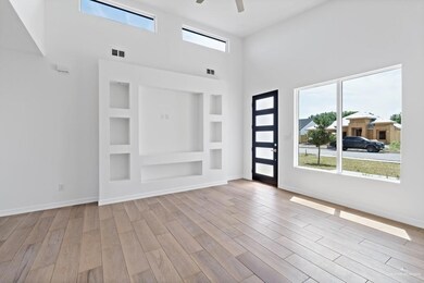 Unfurnished room with built in features, a high ceiling, ceiling fan, and light wood-type flooring