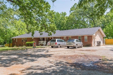 Ranch-style home with fence, gravel driveway, and brick siding