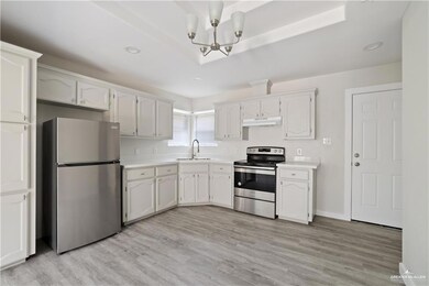 Kitchen with stainless steel appliances, under cabinet range hood, light countertops, light wood-style flooring, and recessed lighting