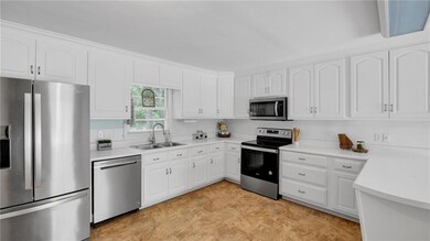 Kitchen with white cabinetry, light countertops, s