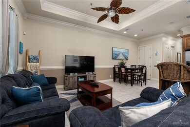 Living room featuring a tray ceiling, light tile patterned flooring, ceiling fan, ornamental molding, and recessed lighting