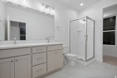 Full bathroom featuring double vanity, a stall shower, light marble finish floors, and recessed lighting