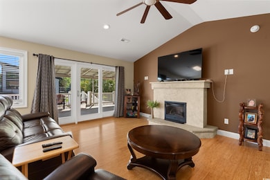 Living room with a high end fireplace, vaulted ceiling, ceiling fan, light wood-style flooring, and baseboards