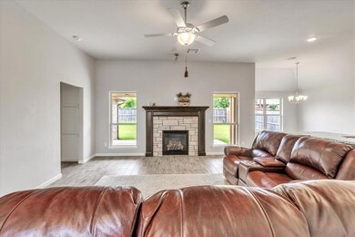 Living room featuring light wood-style flooring, a chandelier, baseboards, and a ceiling fan