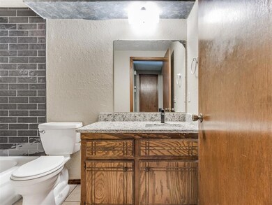 Bathroom with a textured wall, vanity, a washtub, 