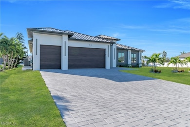 View of front facade with a standing seam roof, a front yard, a metal roof, an attached garage, and decorative driveway