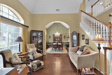 To the left of the entry is the living area and dining room with hardwood flooring and arched doorways.