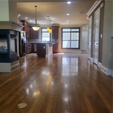 Kitchen with open floor plan, a breakfast bar, oven, tasteful backsplash, and dark wood-type flooring