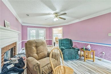 Sitting room featuring ceiling fan, wood finished floors, a fireplace, ornamental molding, and baseboards