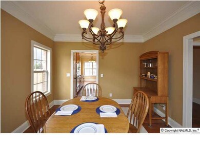FORMAL DINING ROOM WITH CHANDELIER, HEAVY CROWN MOLDING AND HARDWOOD FLOOR.
