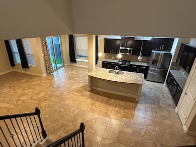 Kitchen with dark cabinetry, open floor plan, decorative backsplash, appliances with stainless steel finishes, and light stone countertops