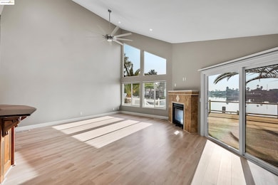 Unfurnished living room with high vaulted ceiling, a water view, a ceiling fan, light wood finished floors, and healthy amount of natural light