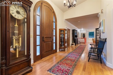 Entryway featuring lofted ceiling, crown molding, a chandelier, and light wood-type flooring