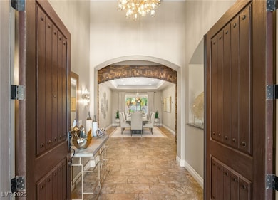 Entryway with stone tile floors, a chandelier, orn