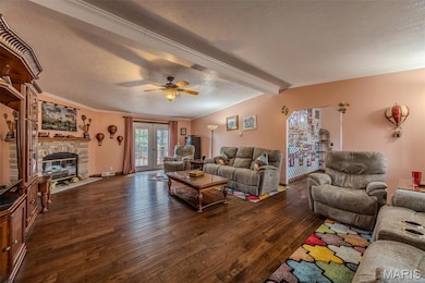 Living room with dark wood-type flooring, a textured ceiling, a fireplace.