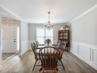 Dining room featuring a chandelier, wood finished floors, a wainscoted wall, a textured ceiling, and a decorative wall