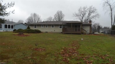 Back of home with covered deck and partially fenced side yard