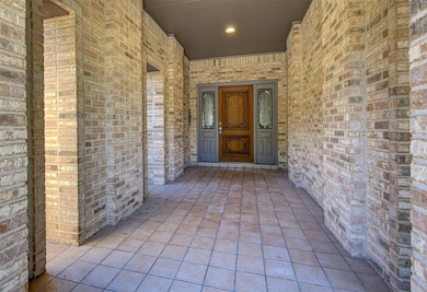Entrance to property featuring brick siding and a porch