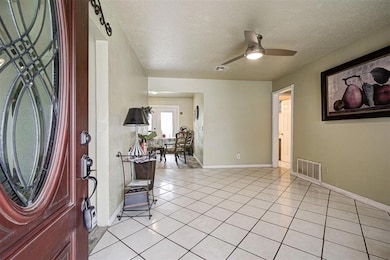 Foyer featuring a textured ceiling, light tile patterned floors, a ceiling fan, and baseboards