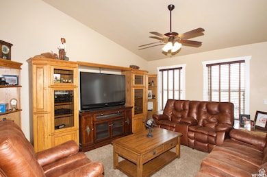 Living area featuring ceiling fan, light carpet, and lofted ceiling