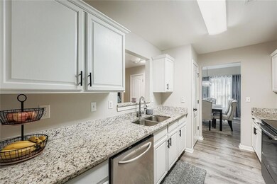 Kitchen featuring appliances with stainless steel finishes, light stone countertops, and white cabinets