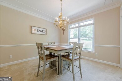 Dining area featuring crown molding, a chandelier, light colored carpet, and baseboards
