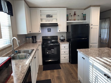 Kitchen with black appliances, open shelves, custom range hood, and dark wood-type flooring