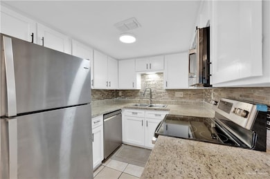Kitchen with visible vents, a sink, white cabinetry, and appliances with stainless steel finishes